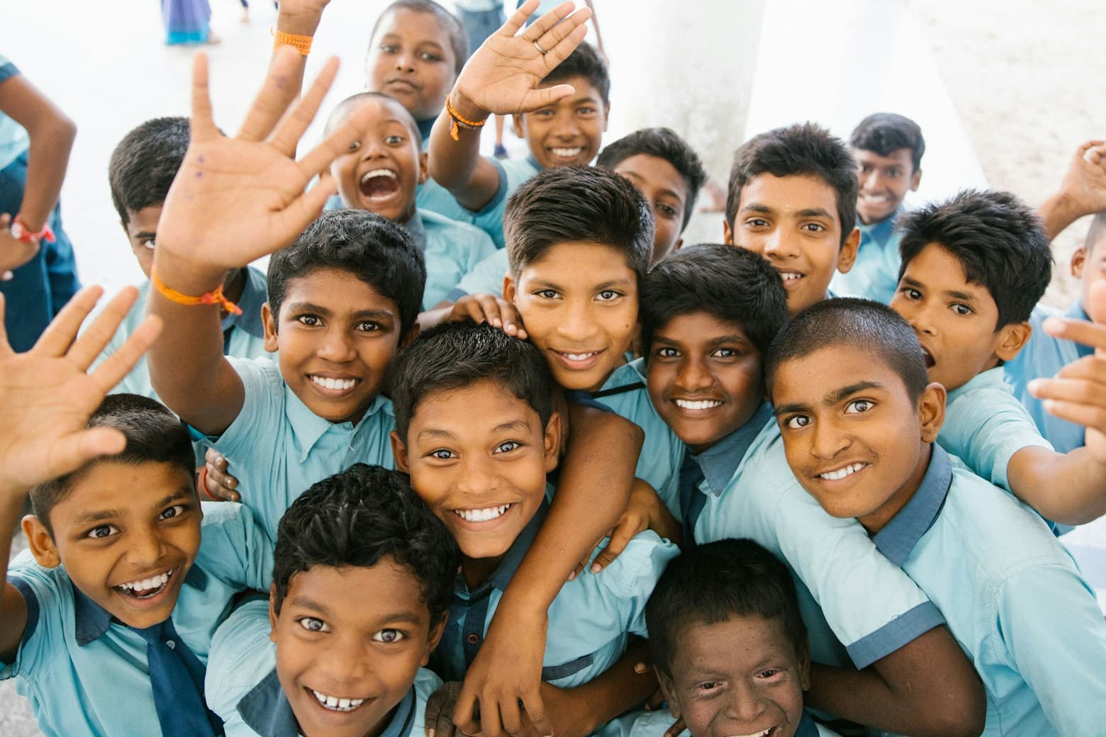 Children from a government school waving at the camera