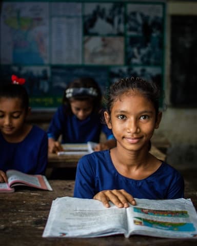 A girl smiling over her open book